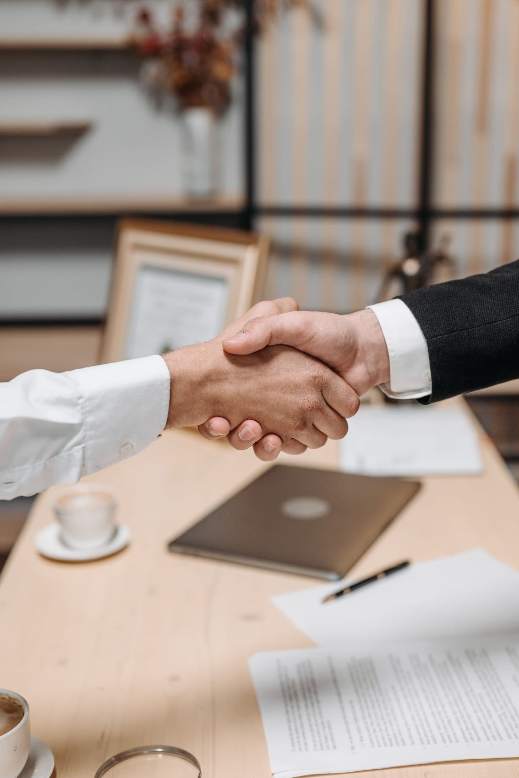 Aperto de mãos fechando uma operação sobre a mesa de reunião
