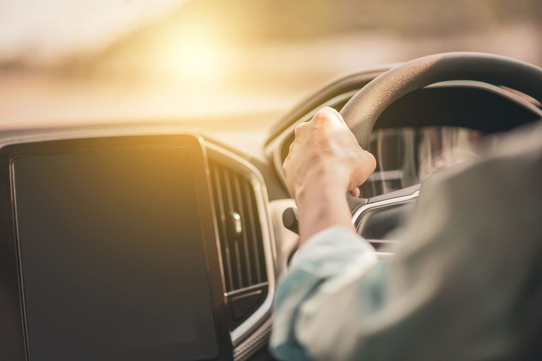 Motorista ao volante em luz de fim de tarde, com o veículo dado em garantia